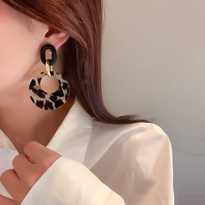 Close-up of leopard print geometric hoop earrings on model with gold connection detail