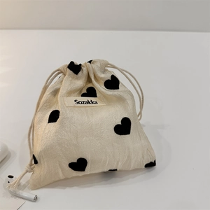 Detail of corduroy drawstring bag with black heart patterns and earphone size reference
