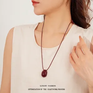 Minimalist wax cord necklace with oval deep red pendant on a female model