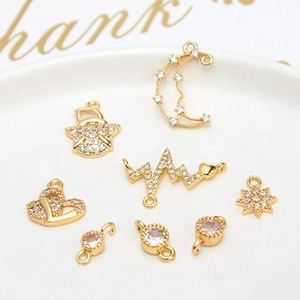 Flat lay of gold plated rabbit and moon charms with micro-pawned zircons on white tray