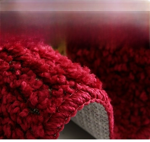 Macro detail of red thick plush door mat with dense loops and non-slip backing