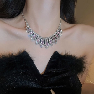 Close-up of model wearing silver geometric tassel necklace with pink and clear crystals