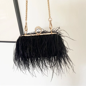 Detail of elegant black ostrich feather evening clutch with golden ring clasp and chain
