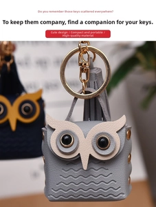 Close-up of light gray leather owl keychain with wave embossing and gold ring hardware