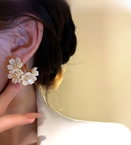 Modella che indossa orecchini a fiore con petali bianco latte e centro dorato