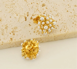 Detailed view of cluster pearl earrings with 18k gold plating on a stone surface