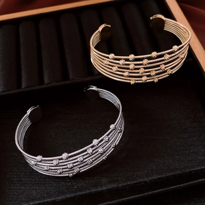 Close-up of gold and silver multi-layer beaded open bracelets on black velvet display