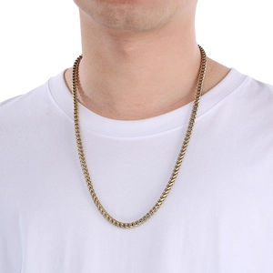 Detailed view of a gold-plated Franco chain worn by a male model on a white T-shirt