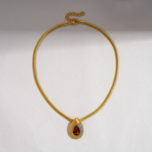 Detail of gold snake chain necklace featuring a red water drop pendant with white zircon stones