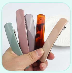 Detail showing long spring hair clips in muted green, pink, purple, amber, and beige