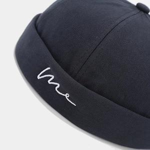 Side view of black canvas docker hat with white cursive me embroidery detail