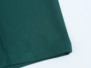Close-up of twill cotton fabric texture and hem stitching on dark green trousers