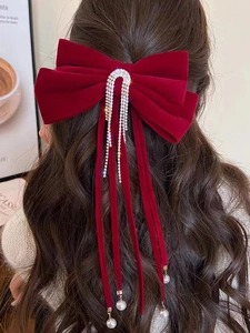 Dettaglio del fermaglio per capelli a fiocco in velluto rosso con nappe di strass