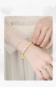 Close-up of gold-colored adjustable open bracelet with shimmering textured surface on wrist