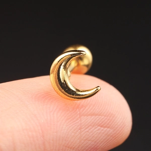 Macro shot of gold moon-shaped stainless steel screw-back earring on a finger