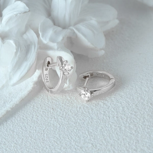 Macro detail of S925 sterling silver stamp and sparkling cubic zirconia stones on huggie earrings