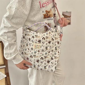 Close-up of white quilted tote bag featuring cartoon patterns and purple woven handles