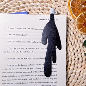 Creative black spilled coffee liquid bookmark tucked into a classic novel with matte texture