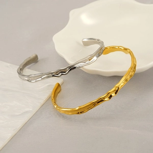 Detailed close-up of textured gold and silver irregular bracelets on a ceramic plate