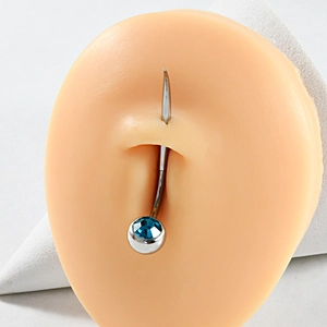 Detail of a 316L stainless steel belly ring with a blue gemstone on a navel model