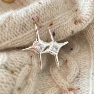 Minimalist 925 sterling silver star stud earrings with zircons on a knit background