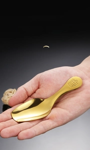 Macro shot of small golden coffee spoon with crown design held in hand for scale