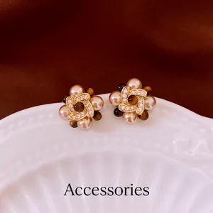 Floral pearl earrings with tiger eye center and diamond accents on white shell tray