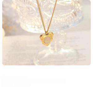 Close-up of heart-shaped gold necklace with opal pendant on blurred background