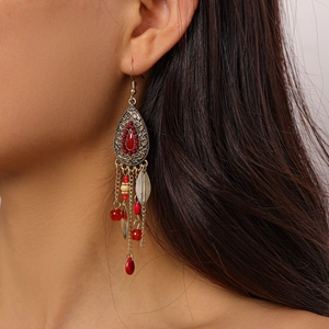 Detail of vintage bronze drop earrings with red beads and leaf tassels on model