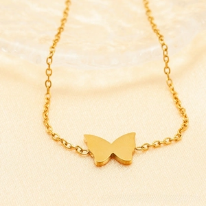 Macro shot of minimalist gold butterfly pendant necklace on soft silk background