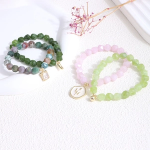 Detailed macro view of faceted beaded bracelets in pink and green with gold charms
