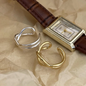 Macro shot of minimalist silver and gold layered crisscross rings on vintage paper