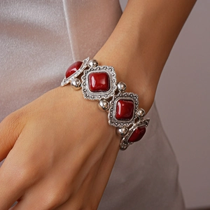 Macro shot of ethnic vintage bracelet featuring red acrylic stones and silver metal texture