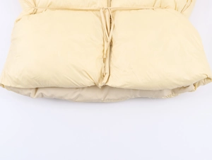 Detailed macro shot of horizontal quilting and adjustable waist drawstring on cream coat