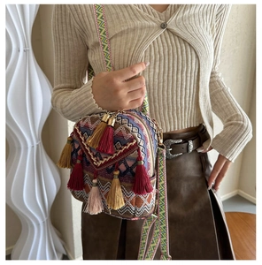 Ethnic style mini backpack with colorful geometric patterns and decorative tassels shown on model