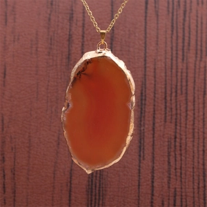 Vue détaillée du pendentif en tranche d'agate orange naturelle avec bordure dorée
