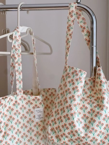 Detailed view of vintage orange floral cotton canvas tote bag with woven brand label