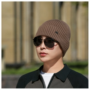 Detail of the brown ribbed knit beanie featuring a black mountain logo patch on the fold