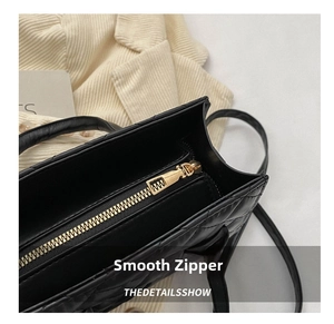 Close-up of a smooth gold metal zipper on a black quilted leather shoulder bag