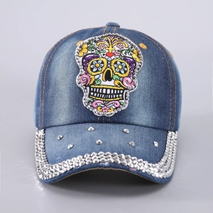 Gros plan de la broderie tête de mort et strass sur le détail de la casquette denim