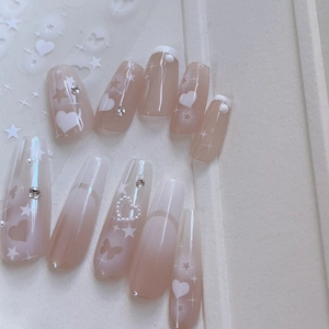 Detail of gradient press-on nails featuring white hearts, butterflies and star charms
