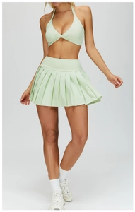 Detailed close-up of mint green pleated tennis skirt and knotted sports bra set