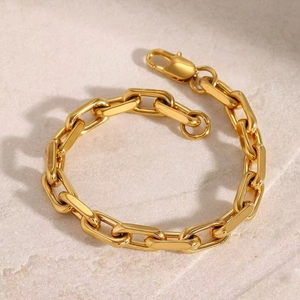 Polished gold stainless steel chain bracelet with lobster clasp on stone texture
