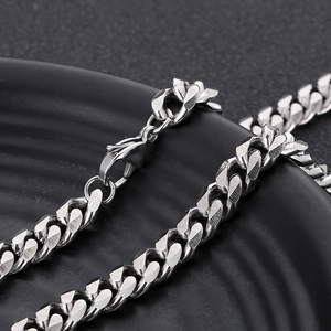Macro view of silver stainless steel Cuban chain with a secure lobster clasp on black base