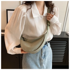 Adjustable strap detail of a light green nylon crescent crossbody bag on a model