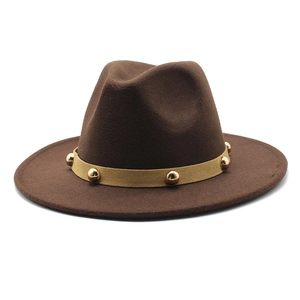 Detail of dark brown fedora hat featuring a beige band with gold metal studs and wide brim