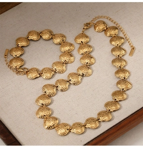 Detailed shot of a gold shell link necklace and bracelet set in a jewelry tray