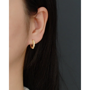 Close-up of a gold S925 silver hoop earring with geometric zircons on a model