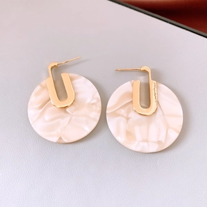 Detail view of 18K gold plated earrings with white marble acetate discs on leather