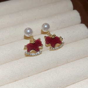 Detail of red rocking horse earring with gold trim, crystals and white pearl stud